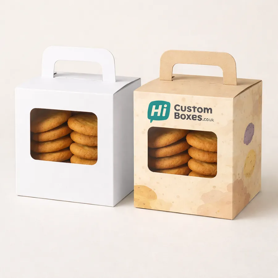 Two square biscuit boxes with carry handles and rectangular windows showing golden cookies inside- class=